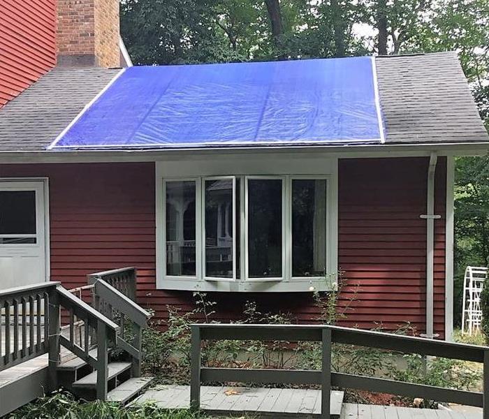 red house with tarp on the roof