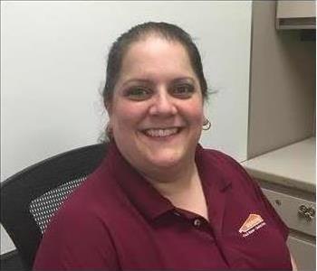 smiling woman with hoop earrings and a maroon Servpro shirt on