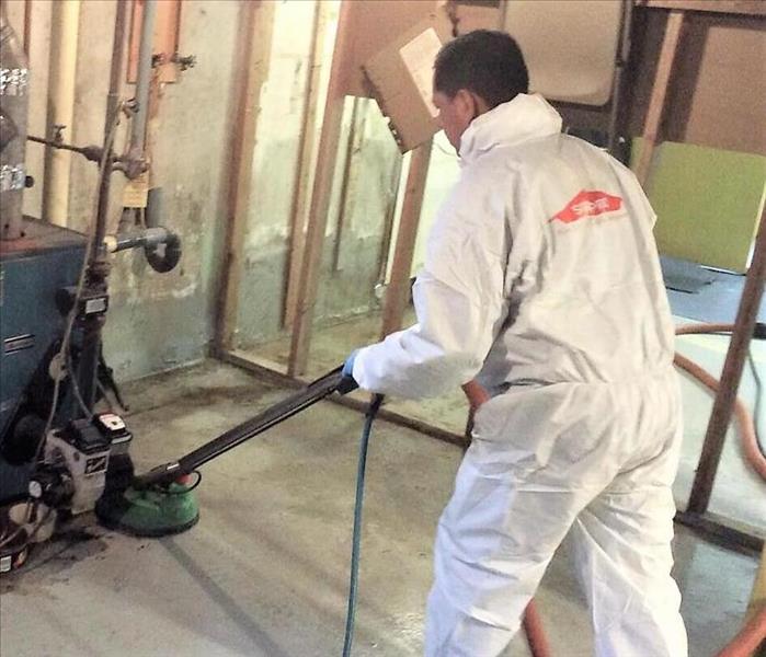 man in servpro protective clothing cleaning a concrete floor