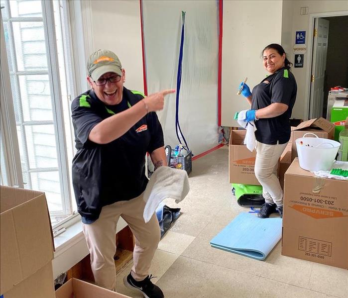 2 servpro employees packing items up and smiling