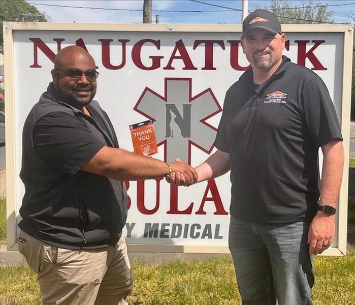 2 men shaking hands in front of a sign