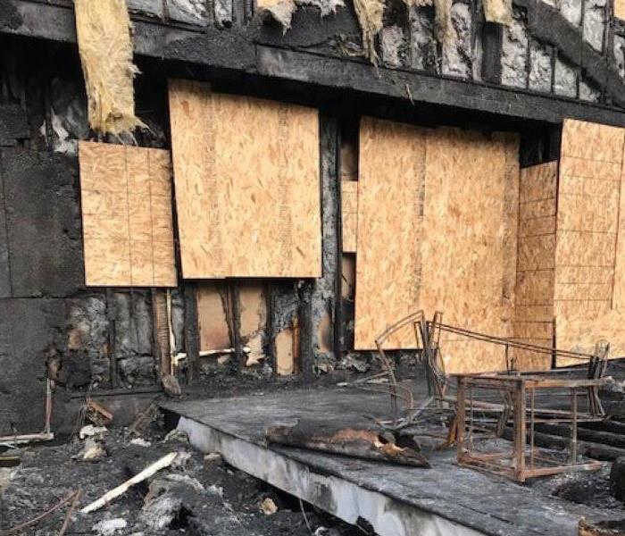 back of a building with fire damage and boarded up windows