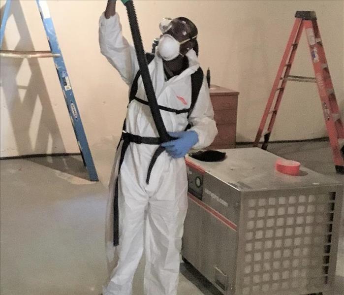 man in protective gear cleaning a ceiling