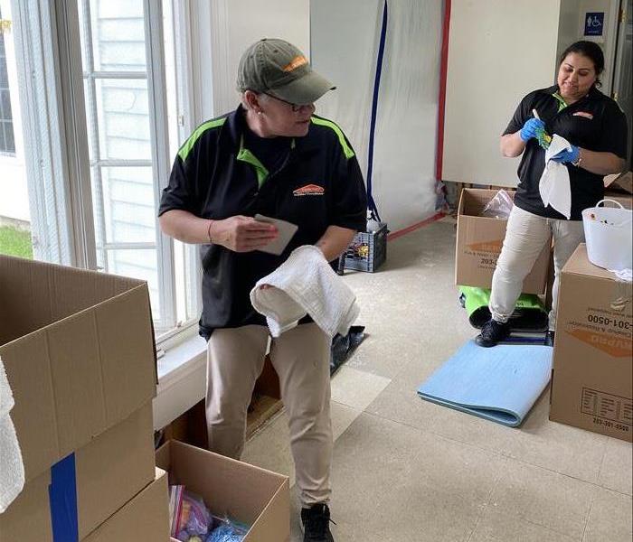 2 servpro employees cleaning items in a house