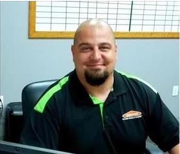 smiling bald man with a black and green Servpro shirt on