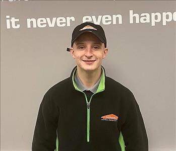 smiling man with brown hair and a black Servpro jacket on